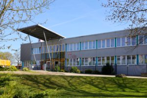 Außenansicht des Medizinischen Versorgungszentrums in Finsterwalde - ein graues Haus mit großen Fenstern, davor eine grüne Wiese